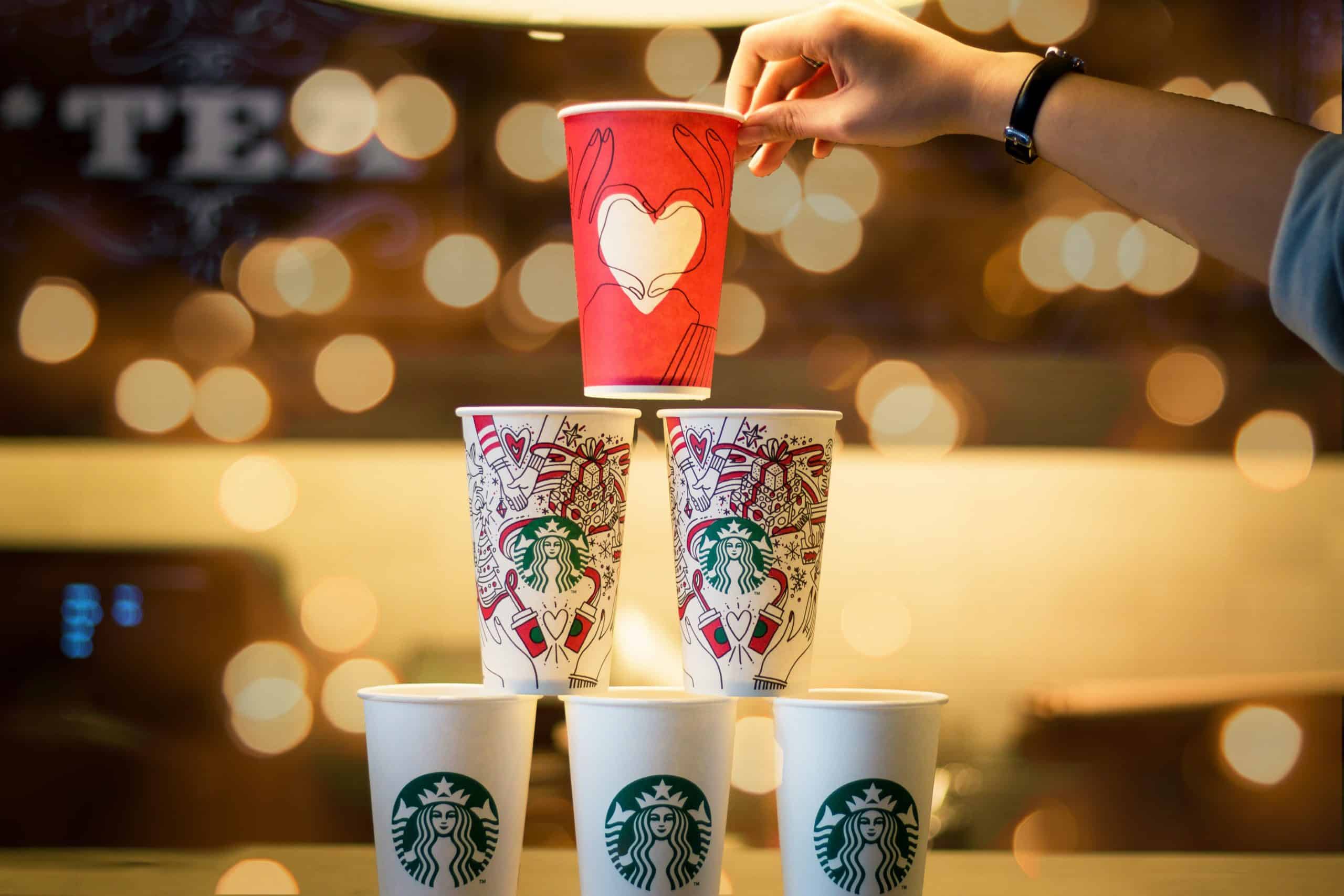 Person stacking Starbucks coffee cups