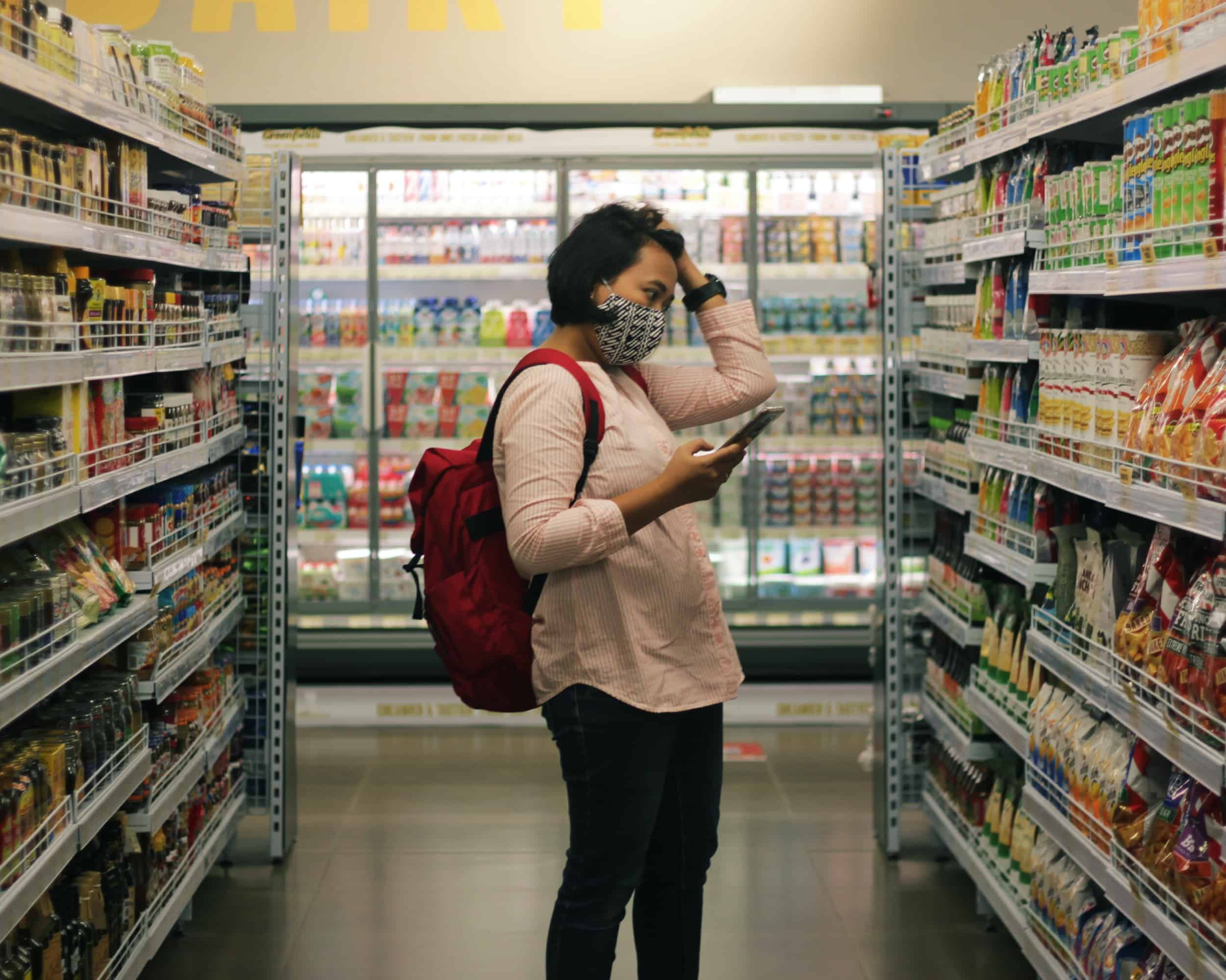 Masked women staring at grocery shelves in grocery store