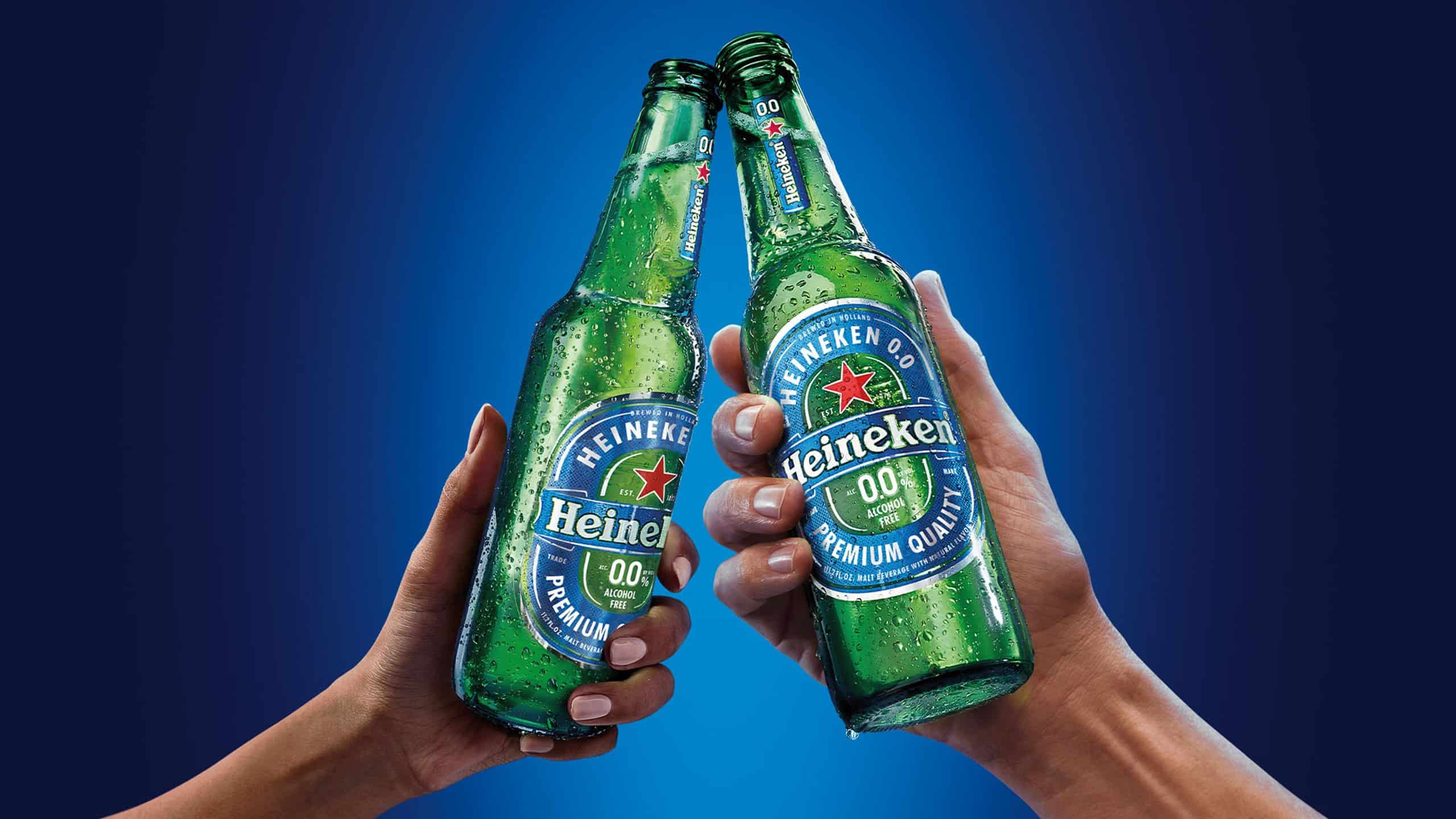 Two hands clanking bottles of heineken zero alcoholic beer