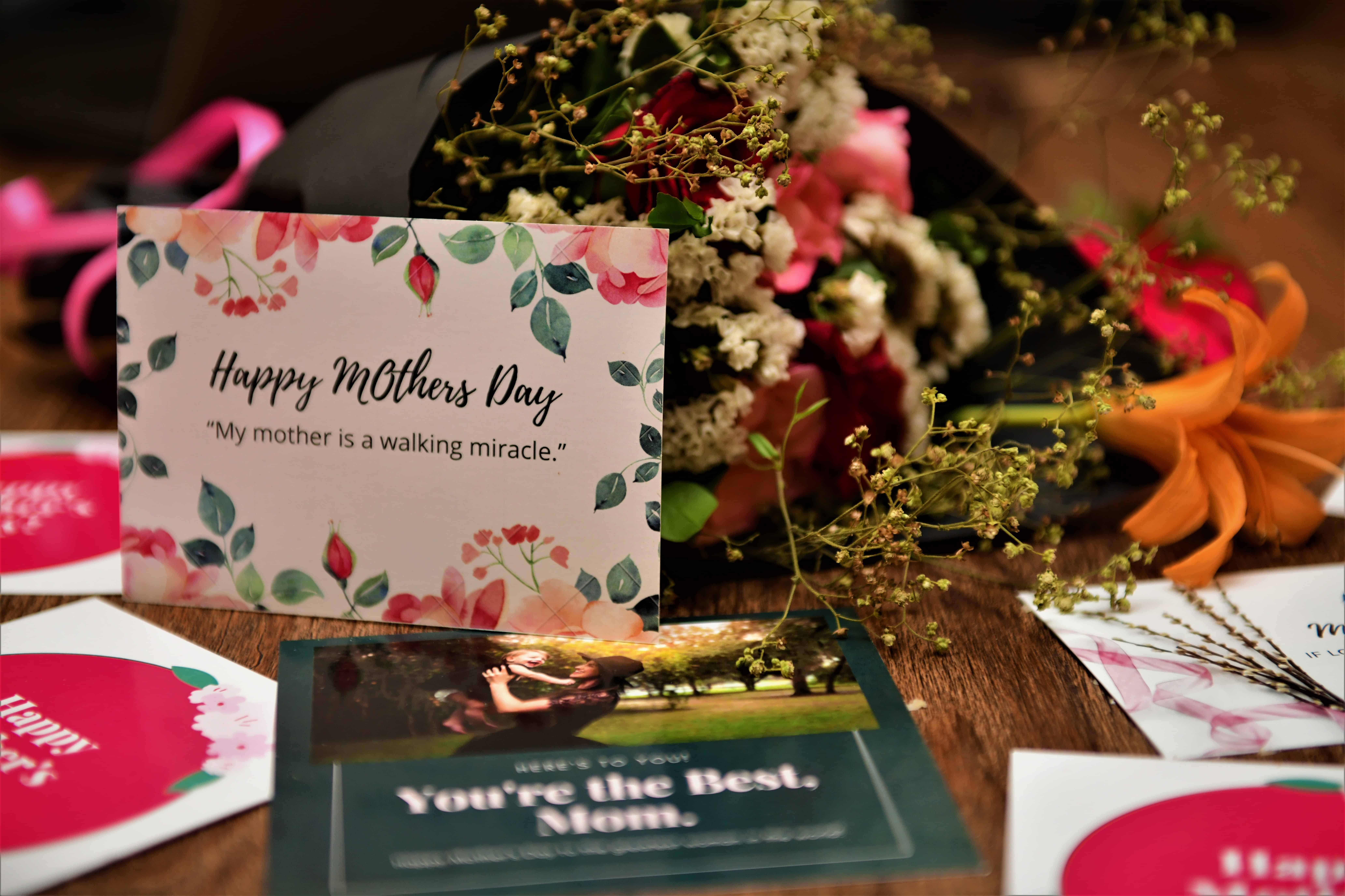 Card that says Happy Mother's Day with flowers on the table next to it.