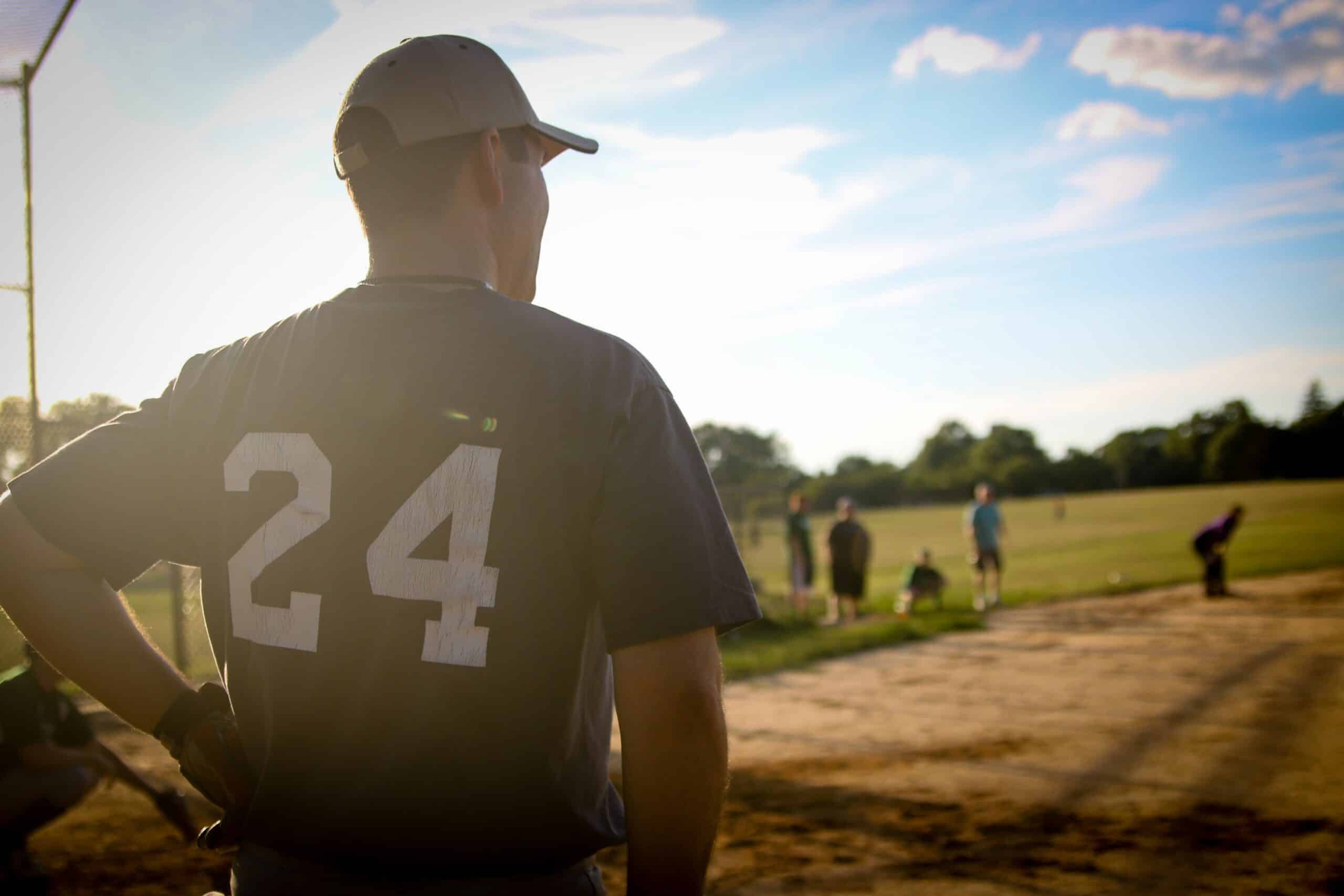 Man in baseball jersey and hat on a baseball field.
