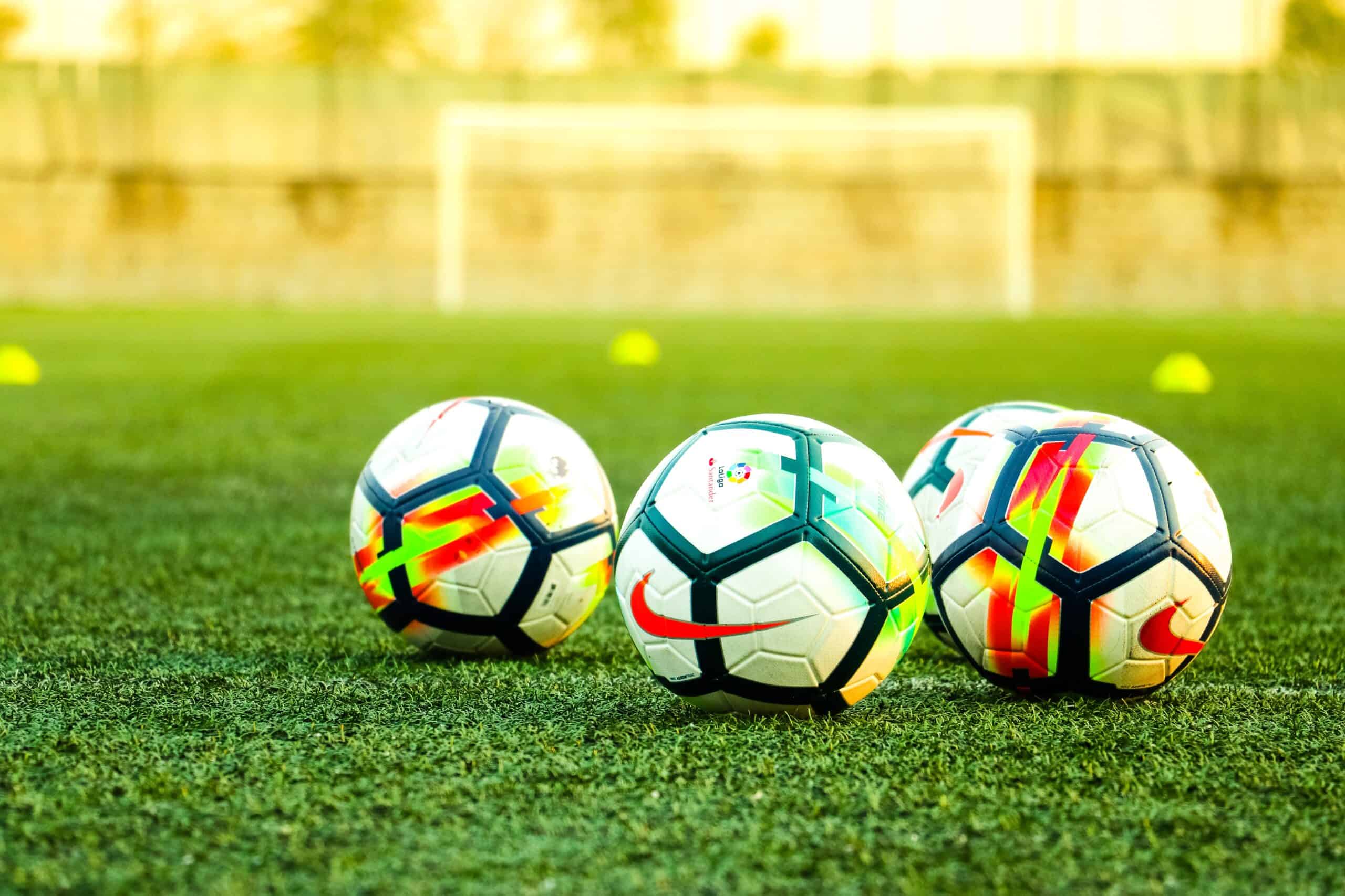 Three soccer balls on soccer field in front of goal