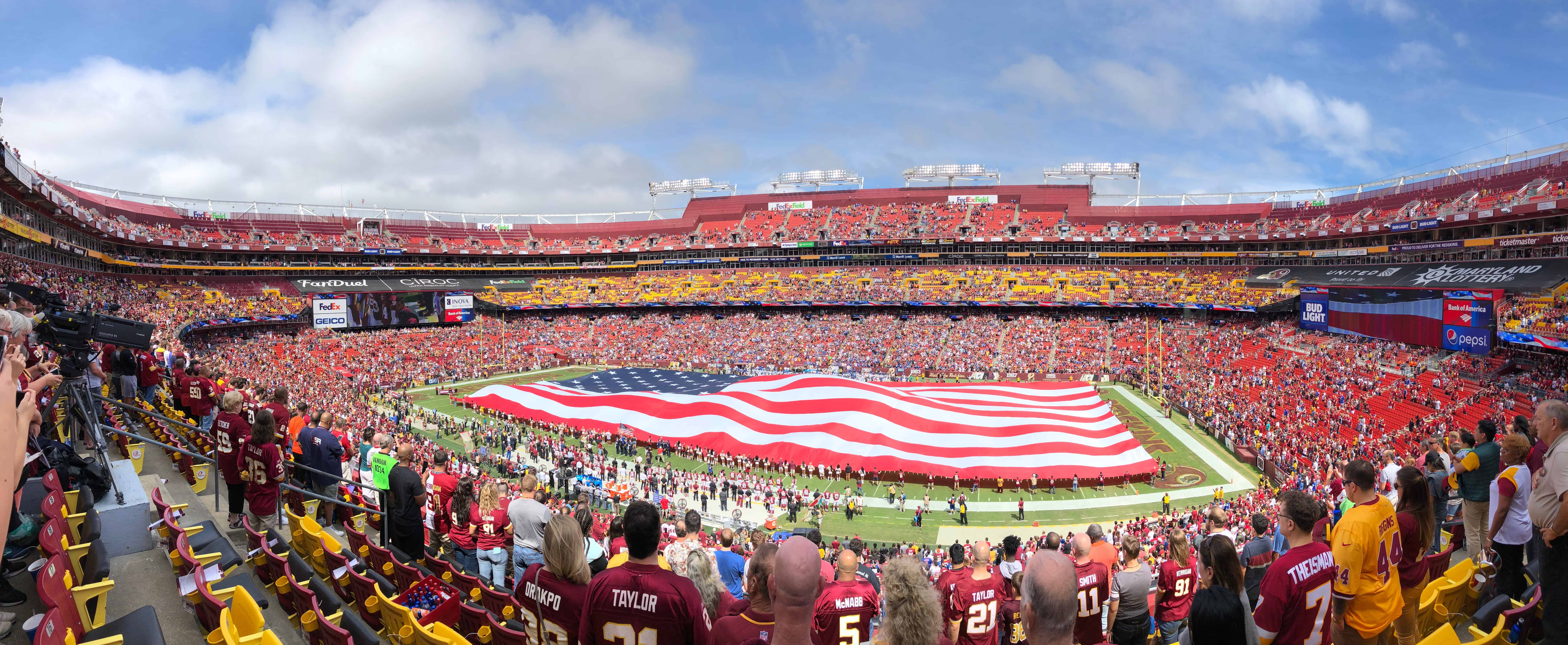 Giant American flag outstretched on NFL football field