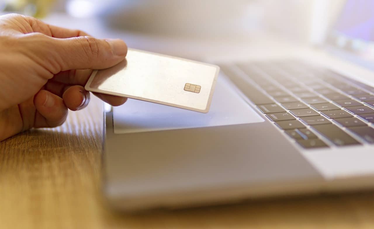 Person holding credit card over laptop