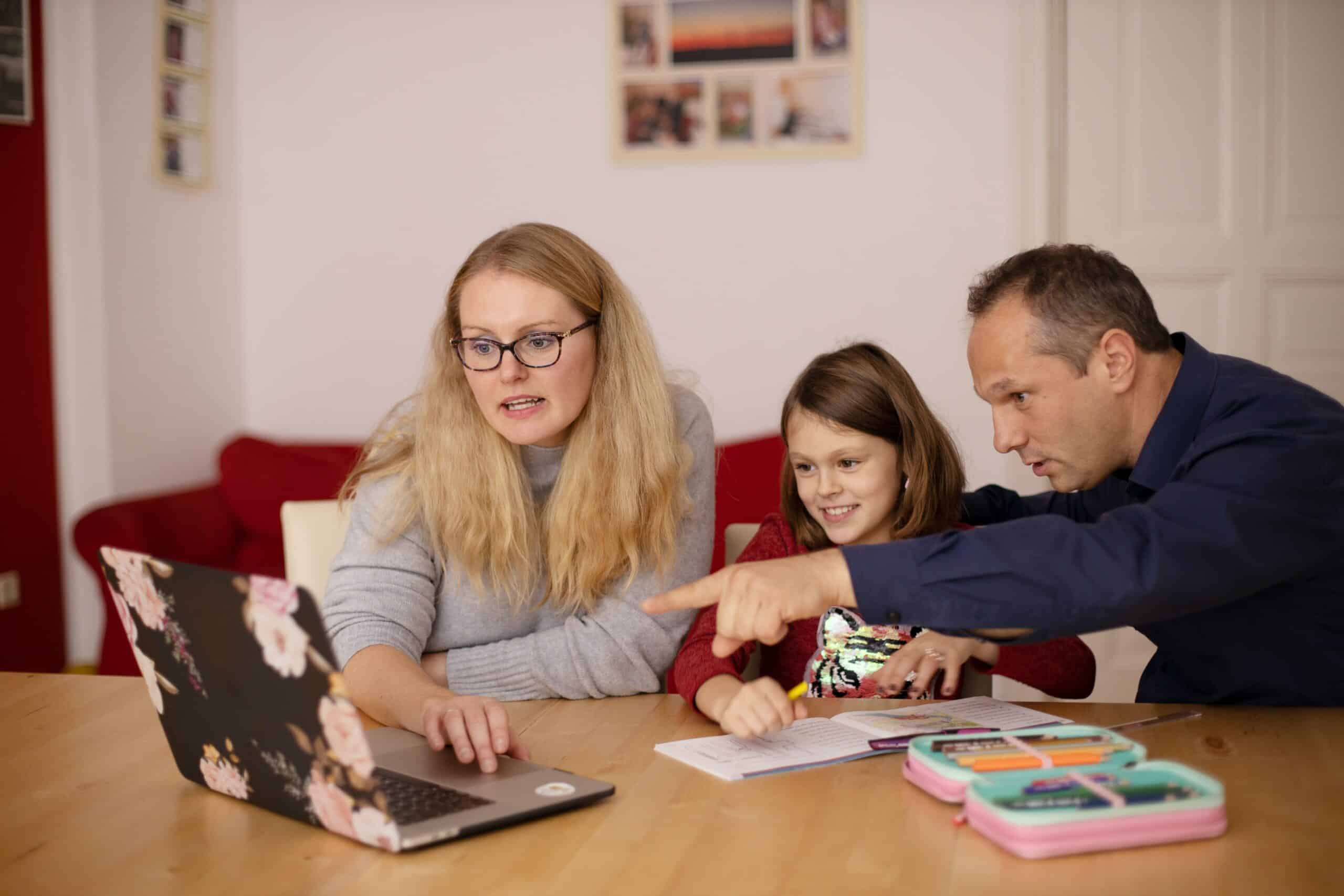 Woman, girl and man working together on a laptop on the desk homeschooling