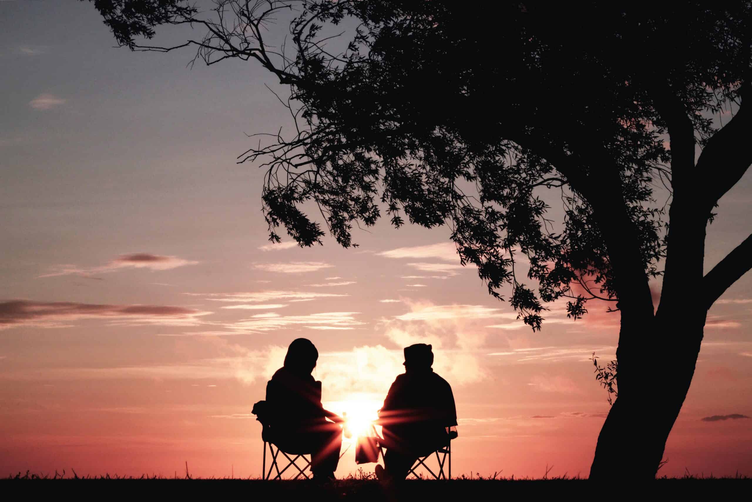 Two adults sitting in chairs looking at sunset