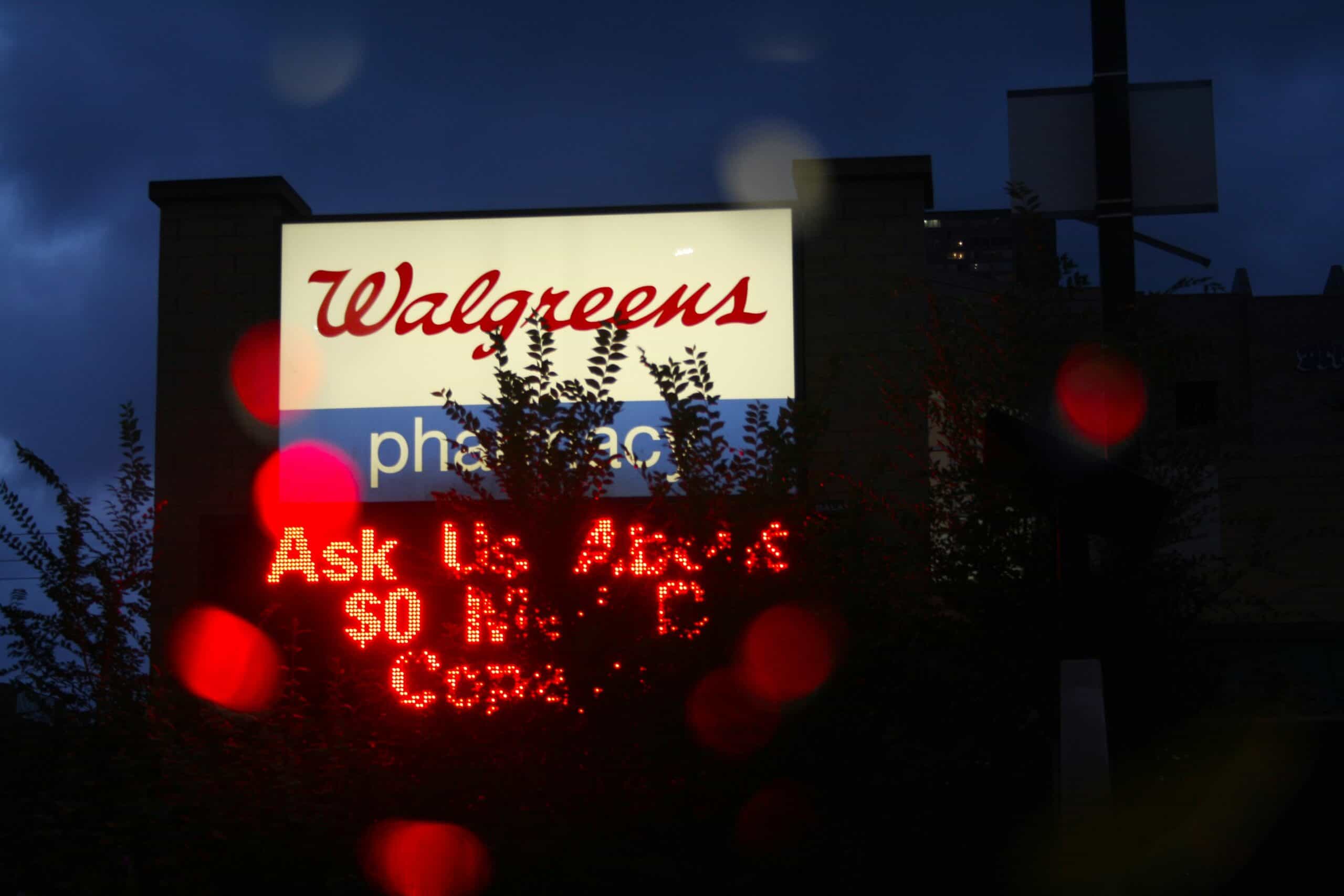 Lighted Walgreens sign partially obscured by a tree