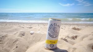 Can of White Claw hard seltzer in sand
